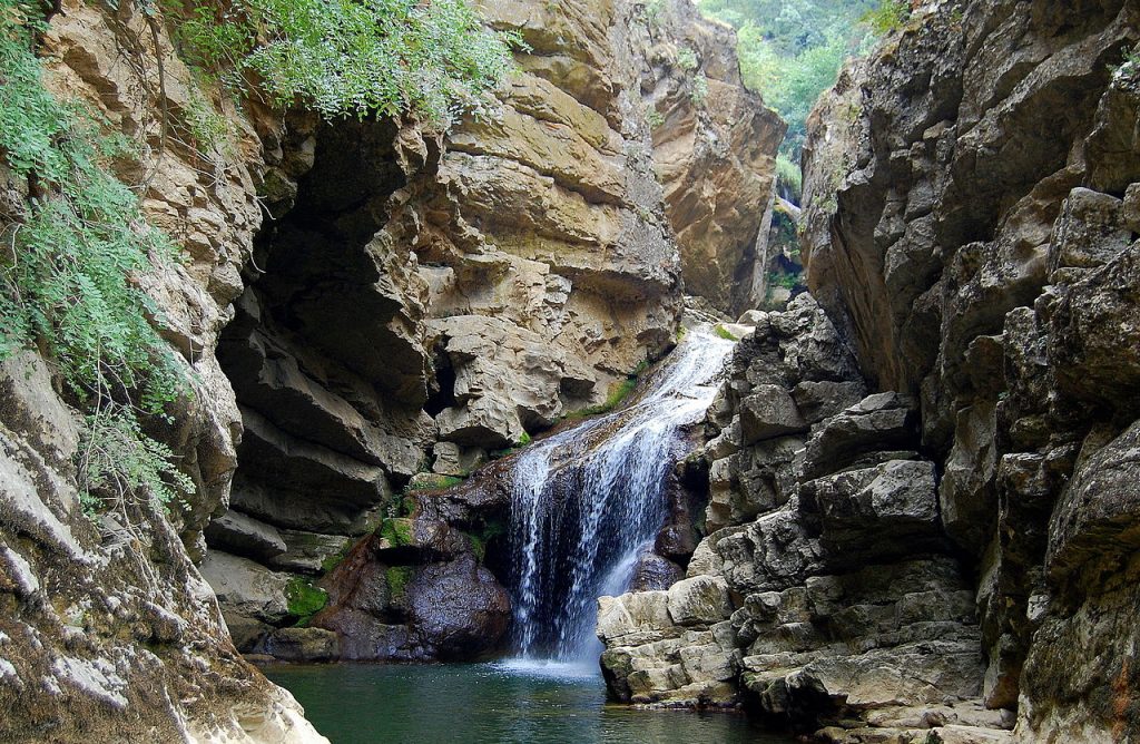 A waterfall falling into a small pool surrounded by rock walls