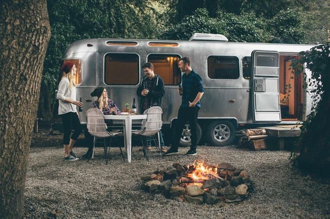 a vintage airstream glamping accommodation, and a group of four people by a campfire