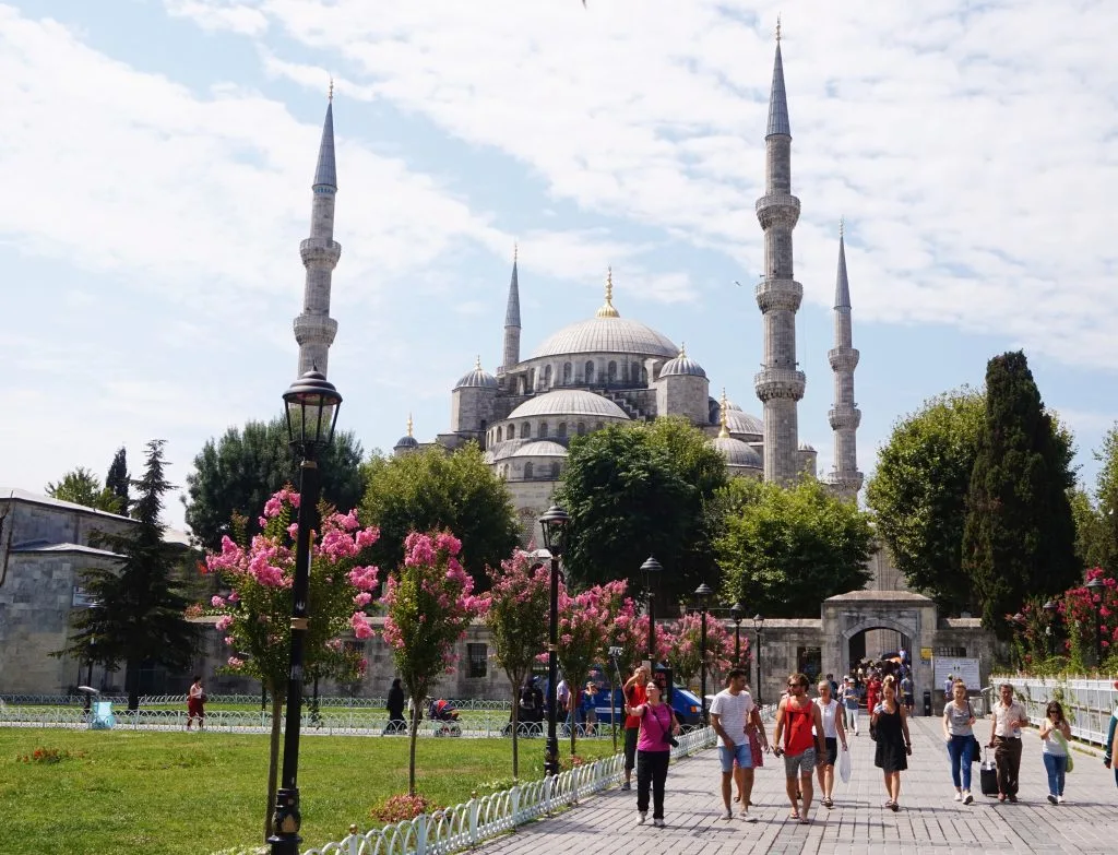 A mosque in the distance, and a park with people walking past it in Istanbul 