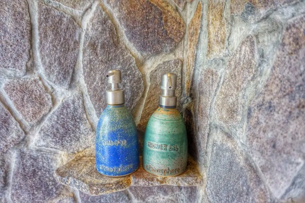 Two bottles of shampoo and shower gel in the corner of a shower