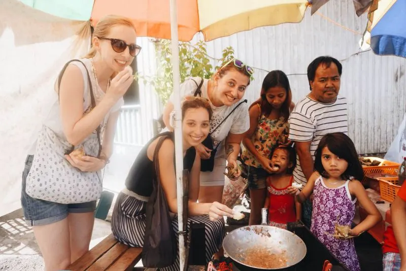 Three tourists and a Philippine family smiling to the camera