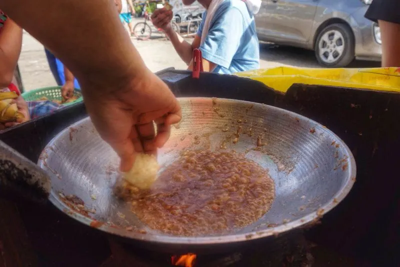 A hand stirring food in a large metal bowl