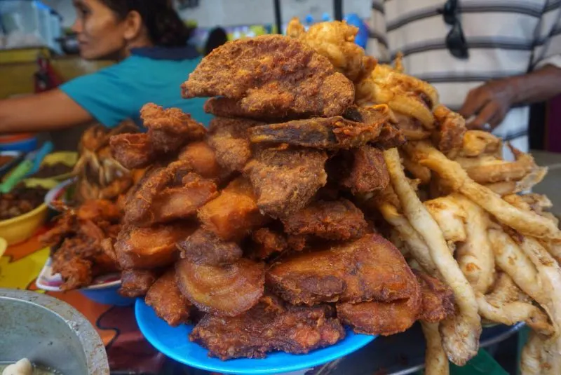 Fried seafood piled on top of a blue dish in a local market