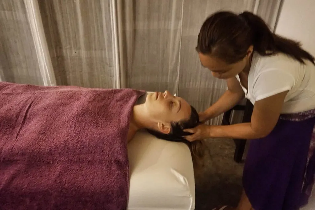 A woman lying in a spa bed as a masseuse massages her scalp