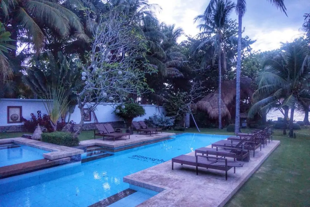 A swimming pool surrounded by sun chairs and vegetation