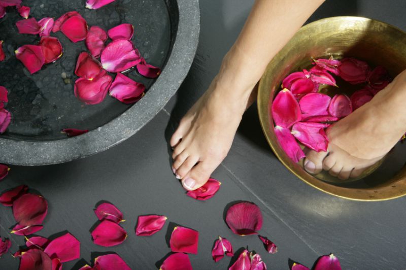 A woman's foot on the floor surrounded by rose petals 