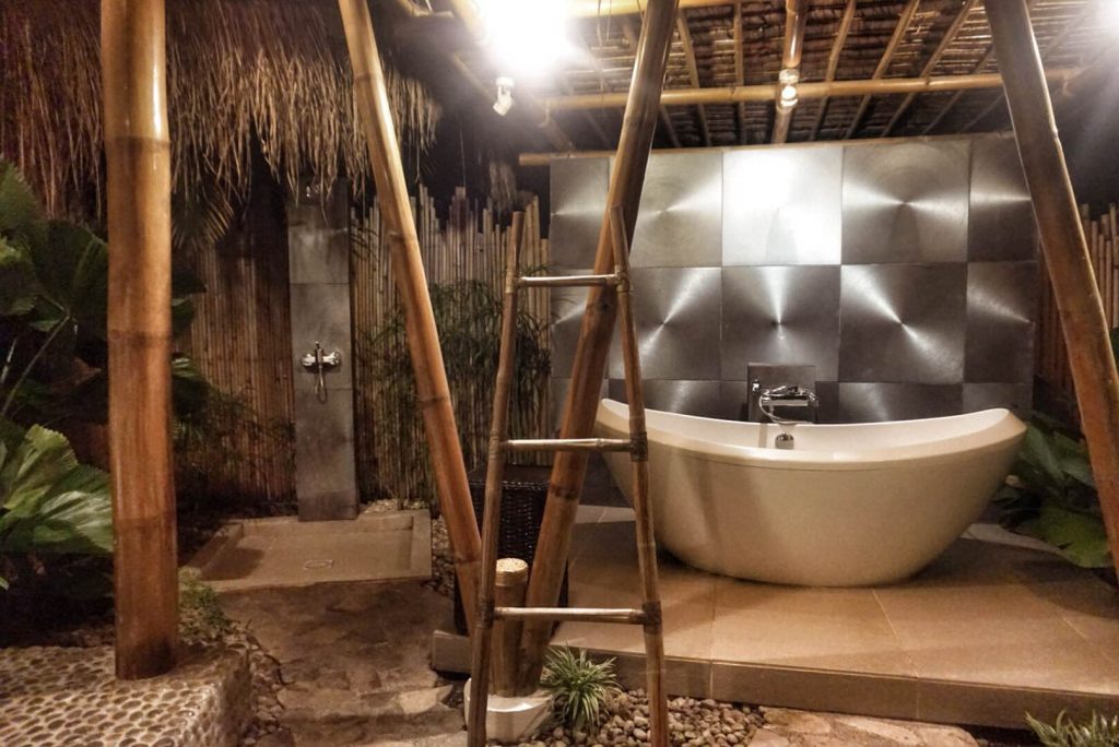 A bathtub and an outdoor shower, image taken at night with artificial illumination