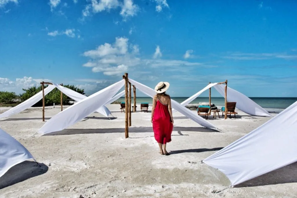 A woman in a red dress walking along the beach 