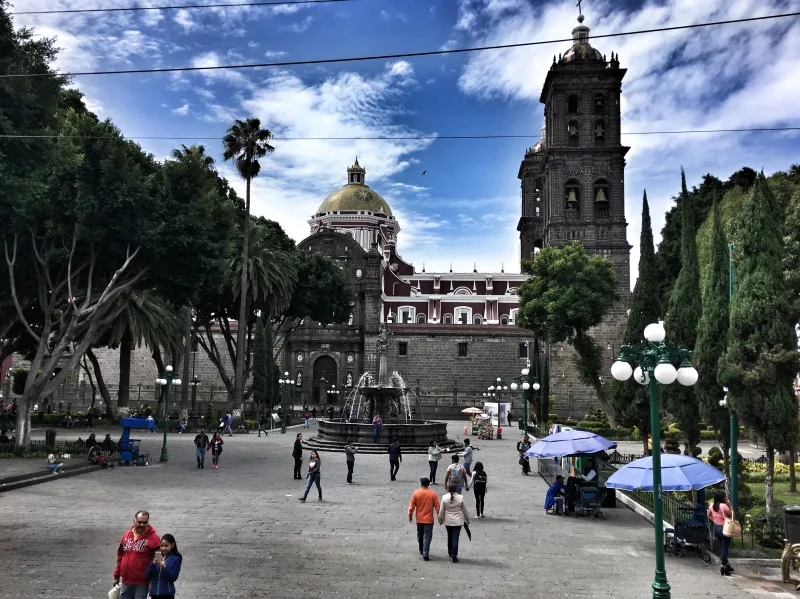 A square in Puebla, with a fountain in the center, and a church in the background