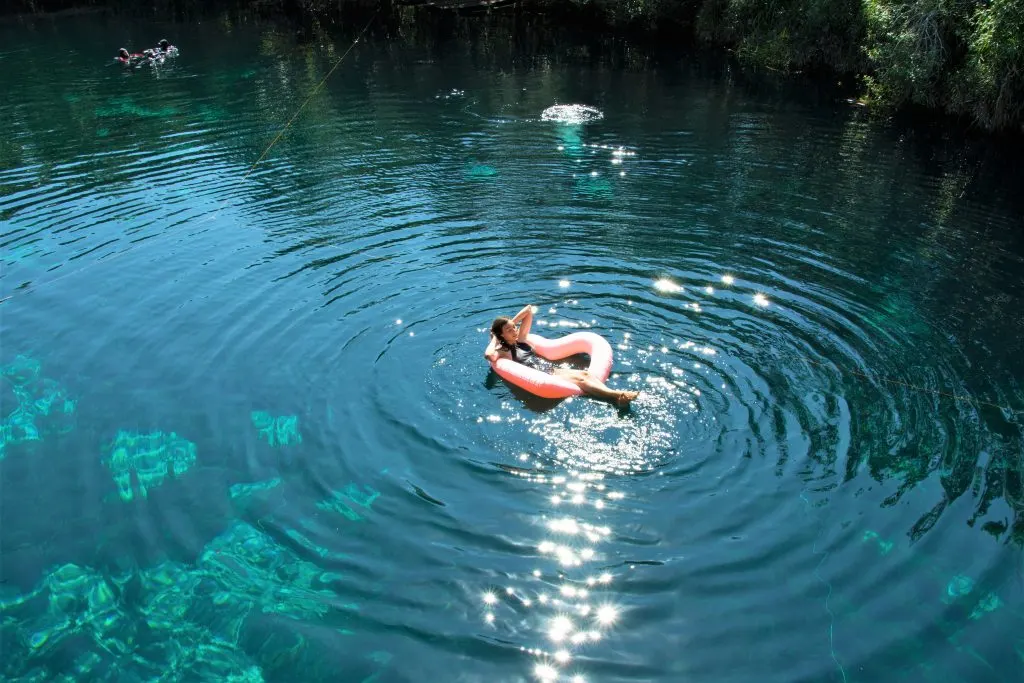 A woman in a heart-shaped floatie in a cenote