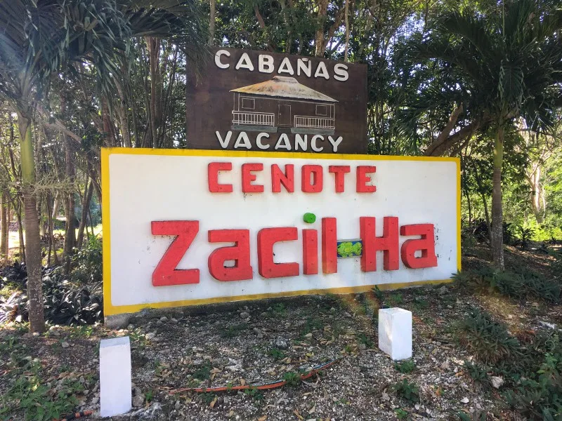 A sign with red letters saying Cenote Zacil Ha 