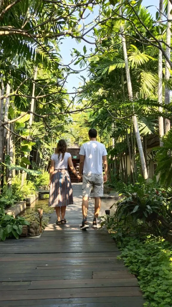 A couple walking on a wooden boardwalk amidst lush vegetation