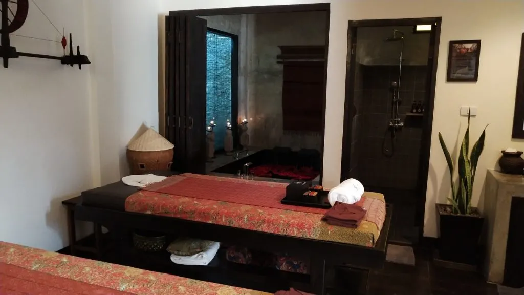 A massage room with a bed, candles, and plants