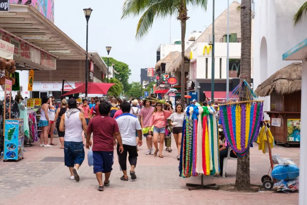 5th Avenue in Playa del Carmen at daytime, with people walking along and colorful stalls on the sidewalks
