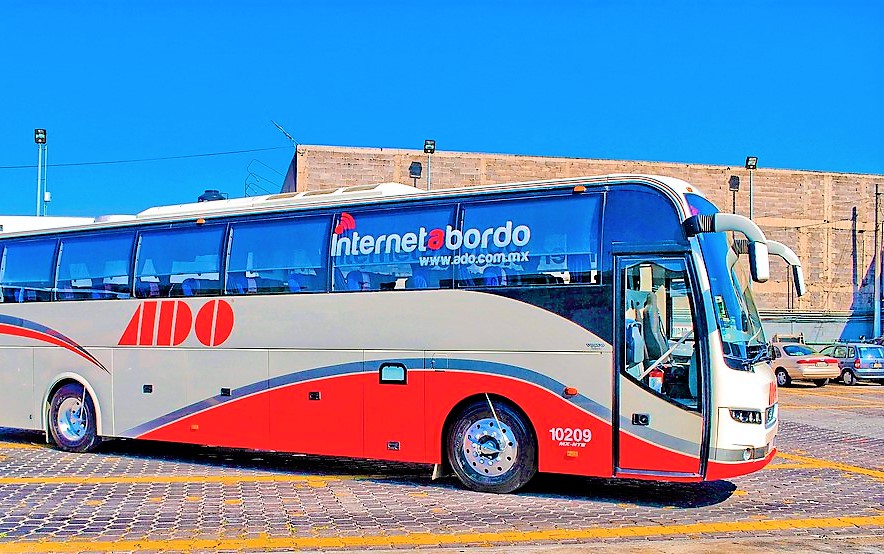 Image of a gray and red ADO bus at the bus station in Playa del Carmen