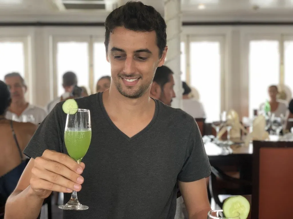 A man holding a champagne glass with a green drink