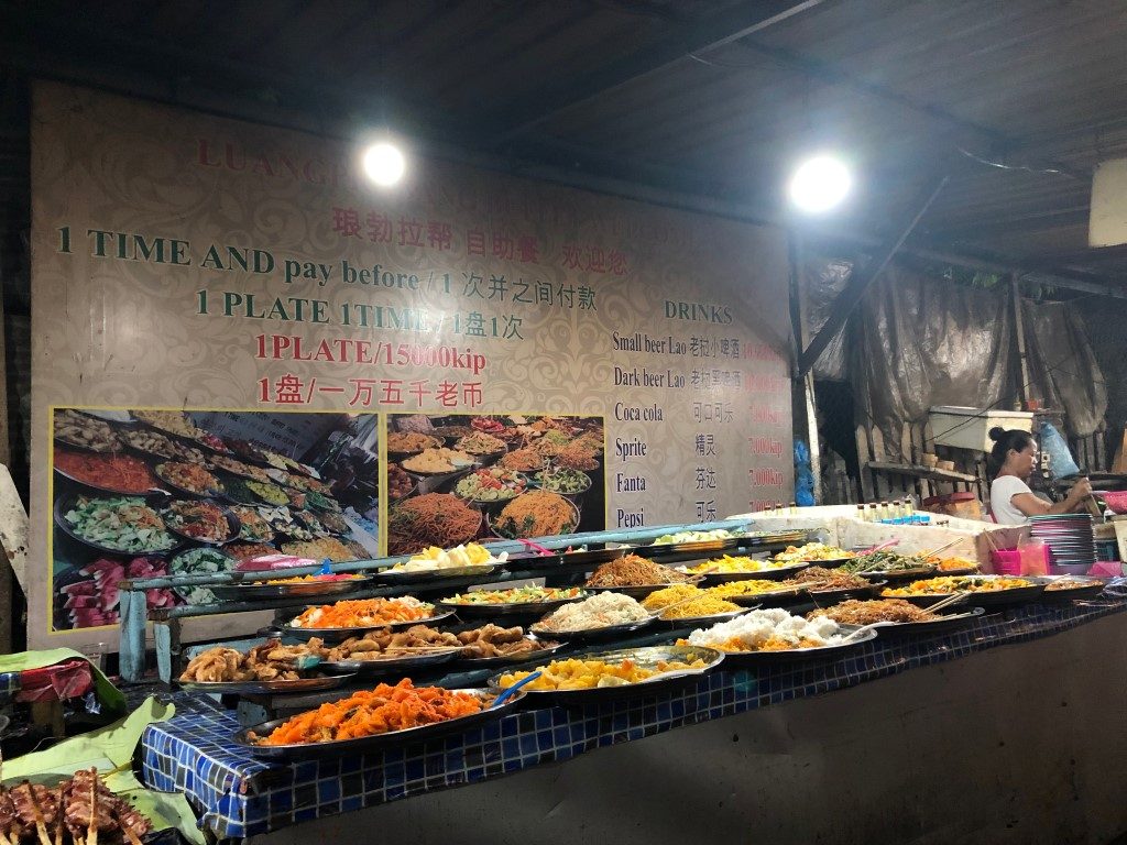 A food market with plenty of trays full of various dishes on display