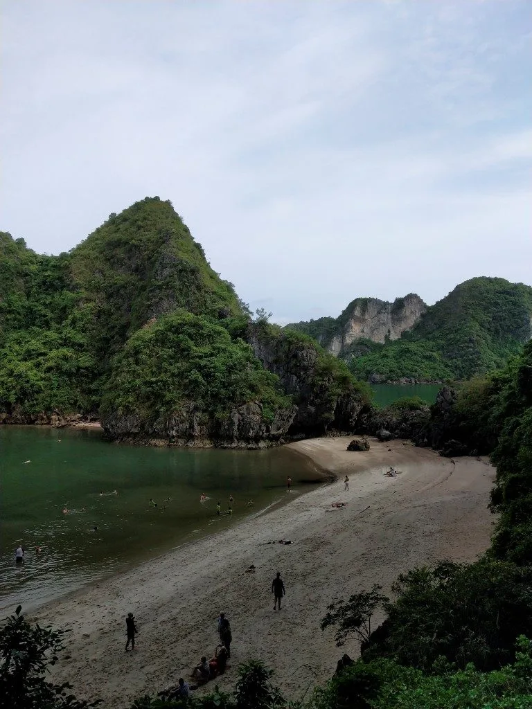 A beach with massive karsts covered in vegetation in the background