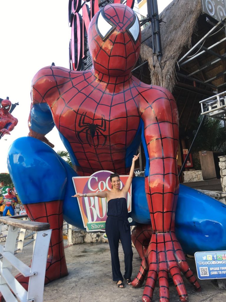 A woman posing in front of a giant spiderman statue in Cancun 