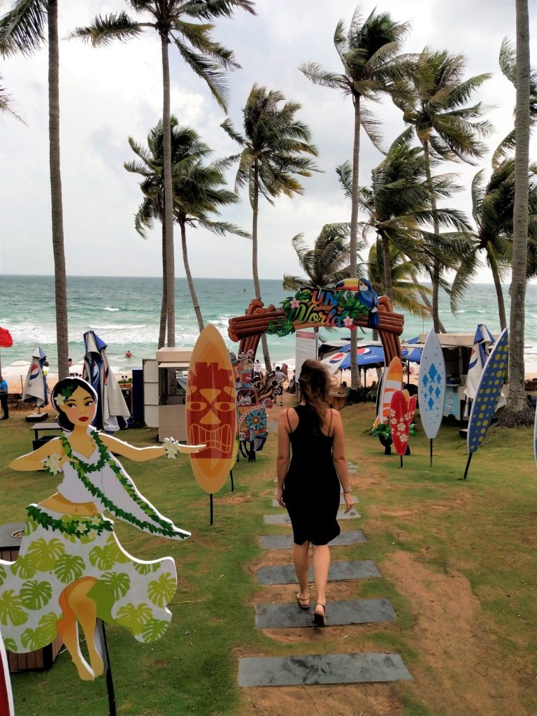 A woman in a black dress walking toward the beach 