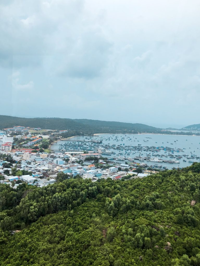 Views of an island's vegetation, the sea, and boats on the water seen from the Phu Quoc cable car 