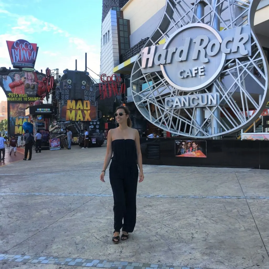 A woman smiling in front of a Hard Rock Cafe sign in Cancun Downtown