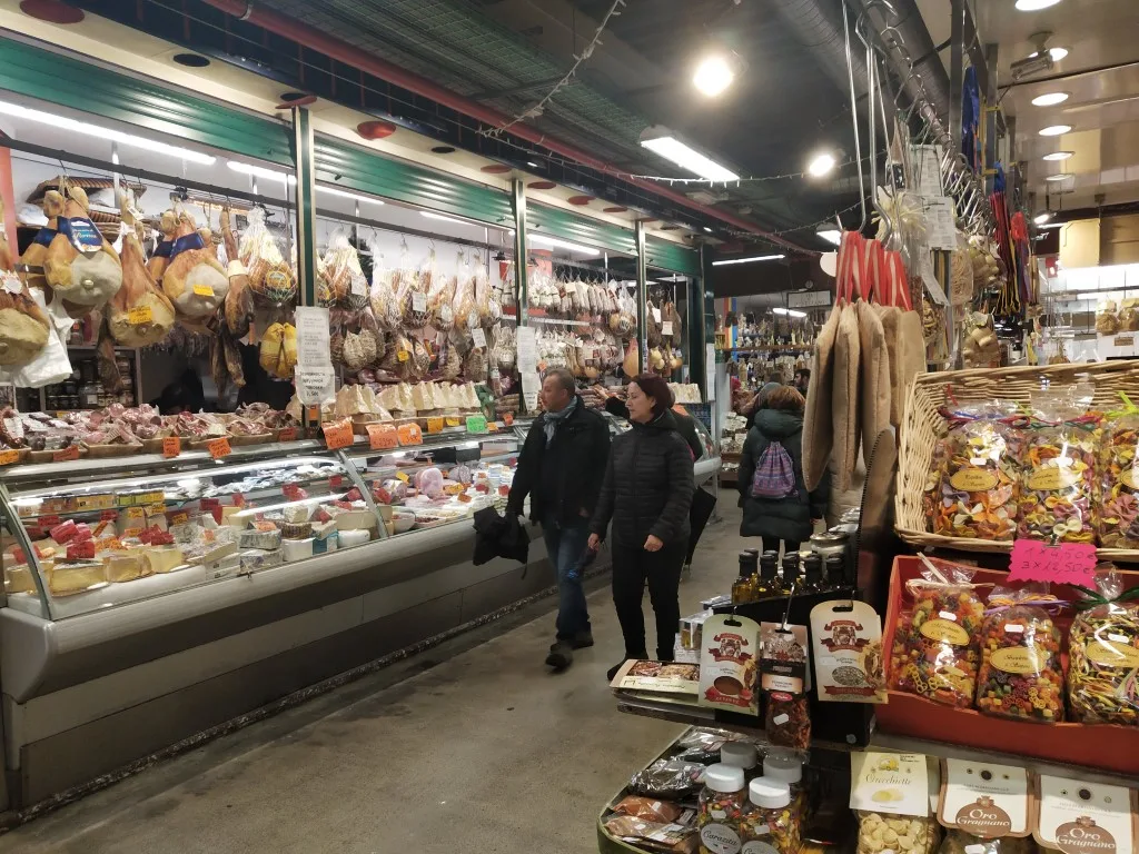 Mercato Centrale, with a stall selling pasta on one side, and a couple walking past a meat shop on the other