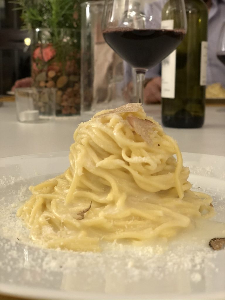 A dish of homemade pasta, and a glass of wine in the background 