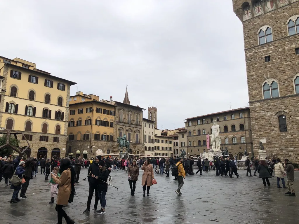 Image of Piazza della Signoria in Florence, with people walking in every direction, and the Neptune fountain in the background 