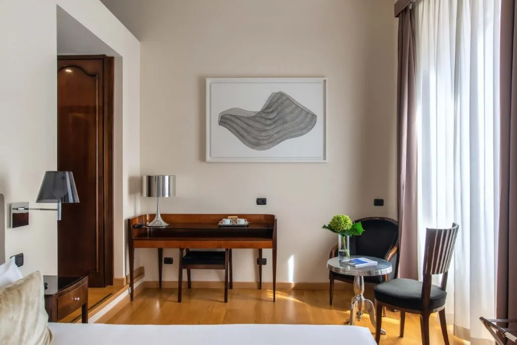 Image of a hotel room with a desk and a small table with two chairs 