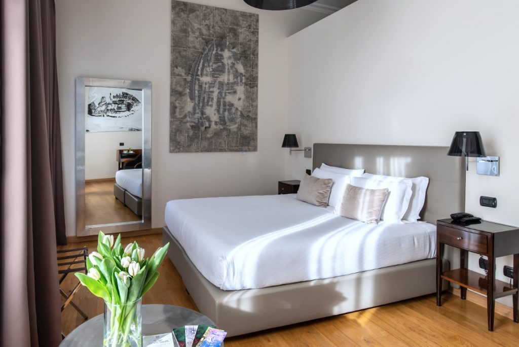 A hotel room with a double bed, two nightstands, and a full-length mirror, inserted in a post about spending 3 days in Rome