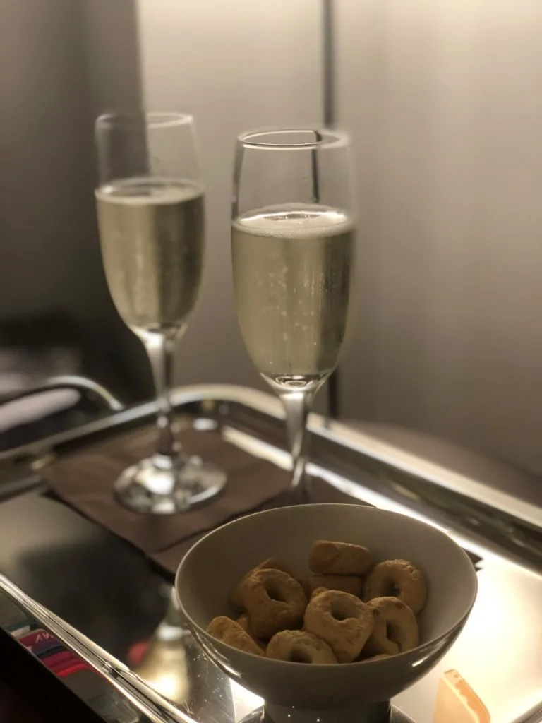 Two glasses of champagne and a bowl with snacks, inserted in a post about Rome itinerary 