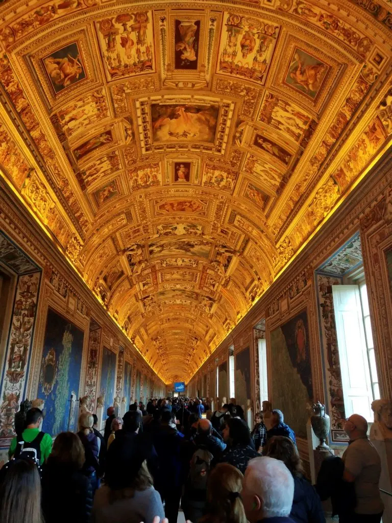 The beautiful ceiling frescoes inside the Vatican Museums, and a long line of people waiting to visit 