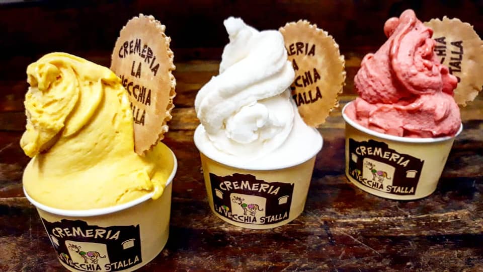 Three ice creams on cups, one of them yellow, the one in the middle white, and the last one pink 