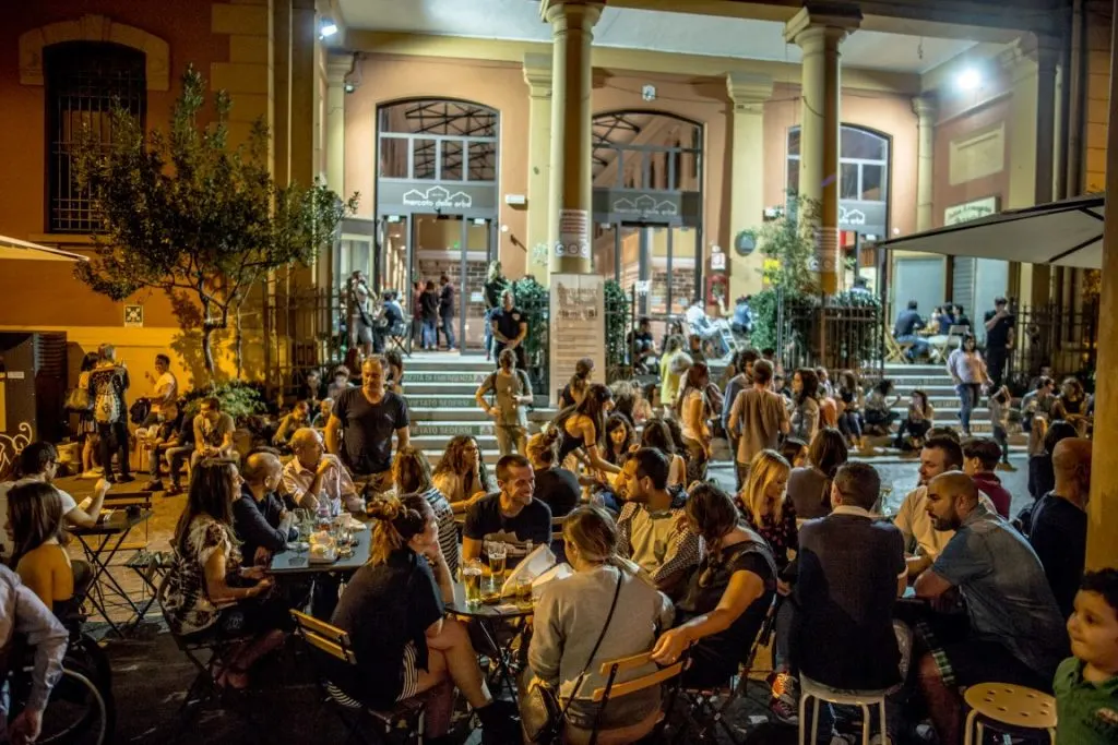 Mercato delle Erbe bustling with people eating and drinking in the patio, inserted in a post about the best Bologna restaurants 