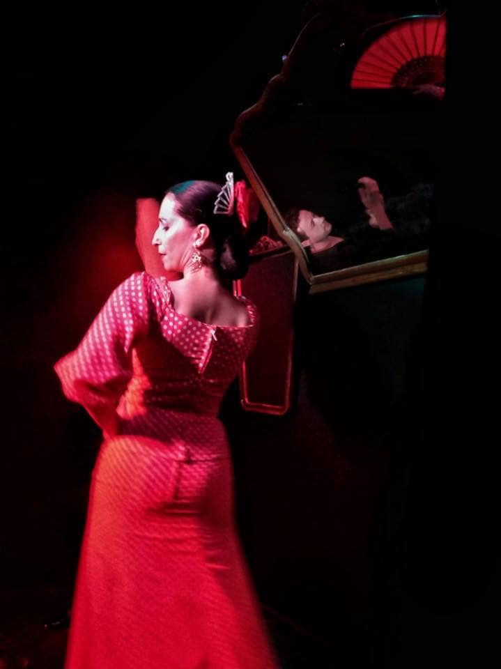 A flamenco dancer in a red polka dress dancing on stage