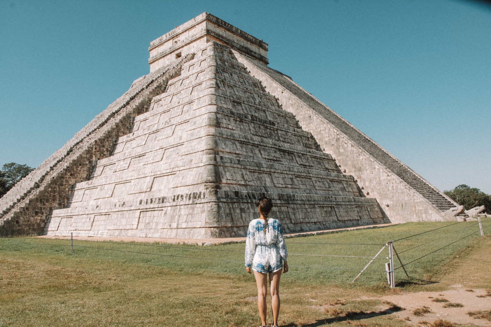 Woman standing in front of the pyramid in Chichen Itza, one of the best day trip from Playa del Carmen.