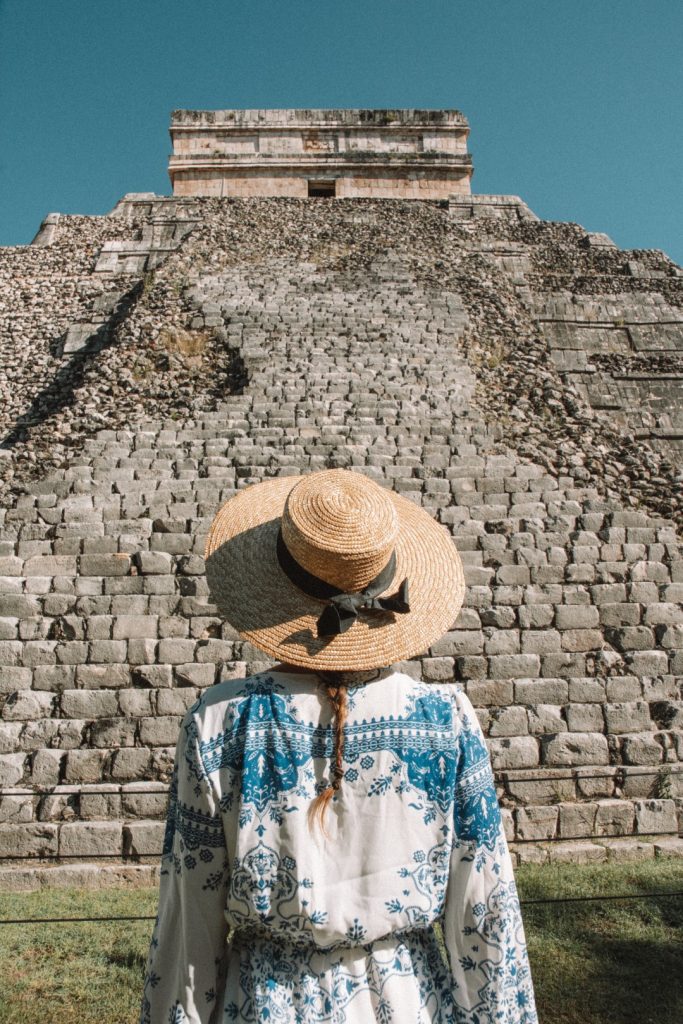 A woman standing in front of Kukulcan Pyramid in Chichen Itza 
