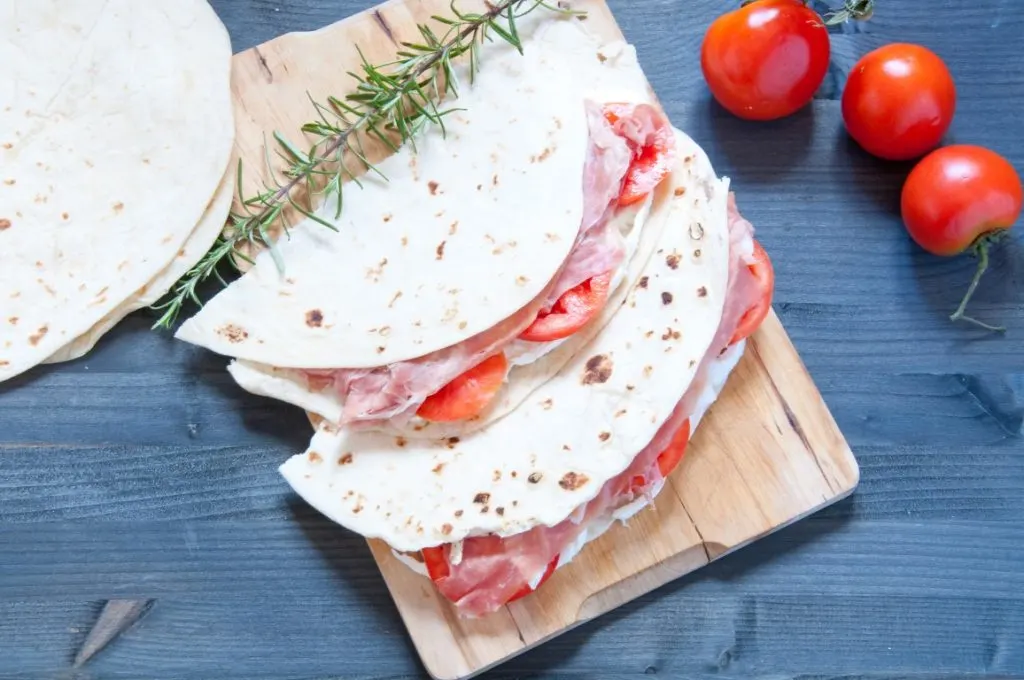 Two piadina romagnola filled with tomato and prosciutto