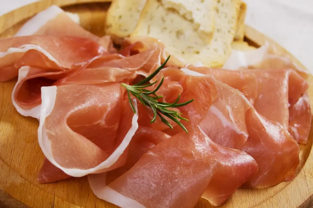 A round wooden board with prosciutto and bread 