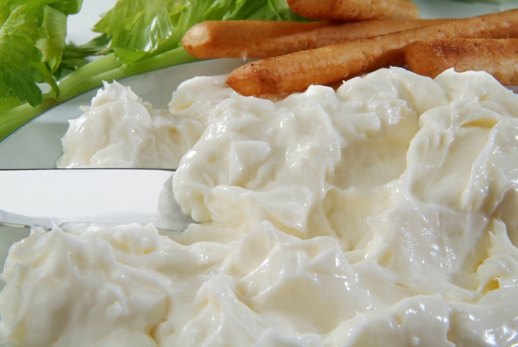 A dish of Squacquerone with breadsticks in the background