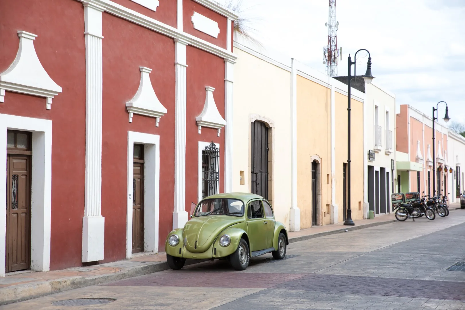 A street in Valladolid, with pastel-colored buildings and a green beetle car parked by the sidewalk