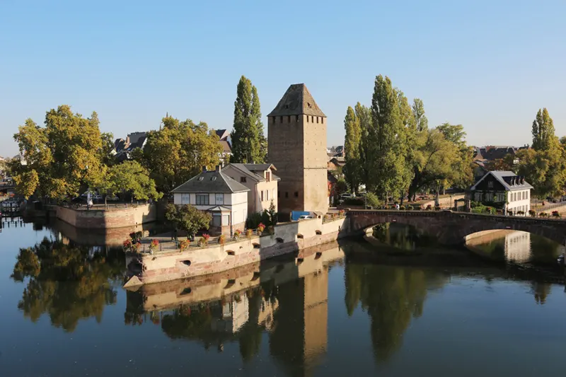 A canal surrounding a tower and a few houses