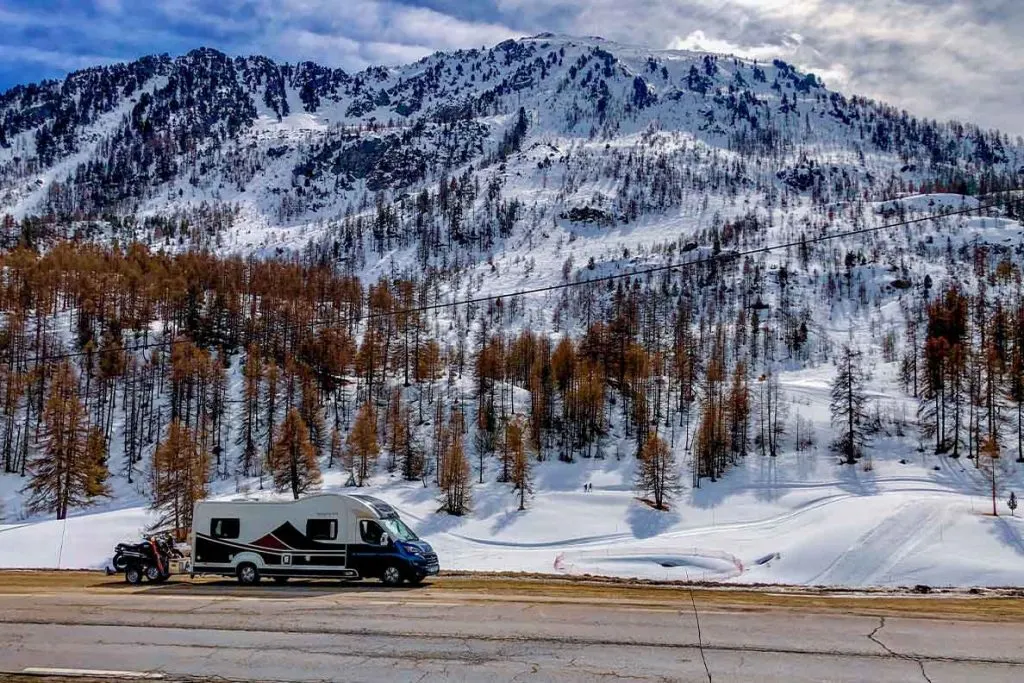 A caravan parked on a road, and a snow-covered mountain in the background