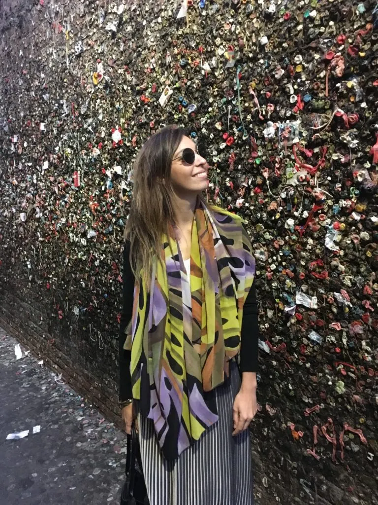 A woman standing in front of a wall filled with bubble gum 