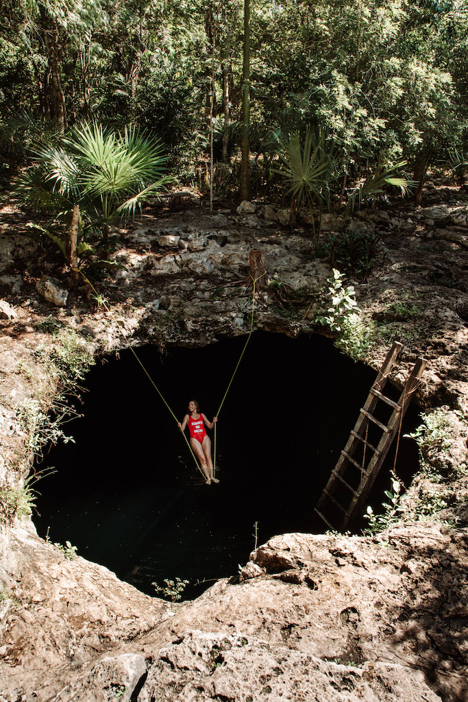 Woman standing on a rope inside Cenote Calavera in Tulum.