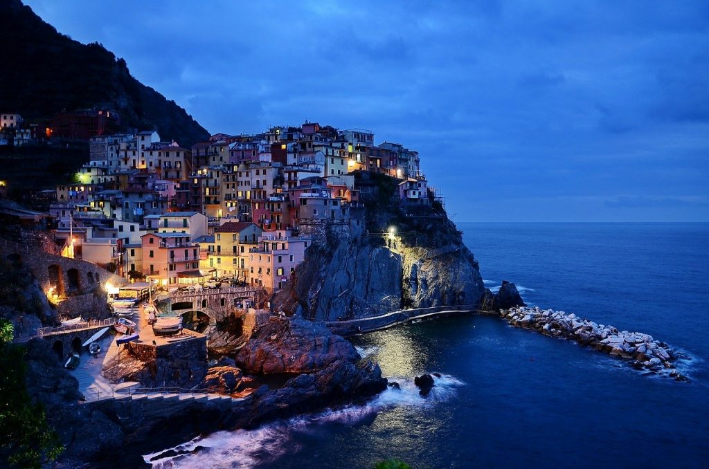 A clifftop town in Cinque Terre, seen from the water at nighttime