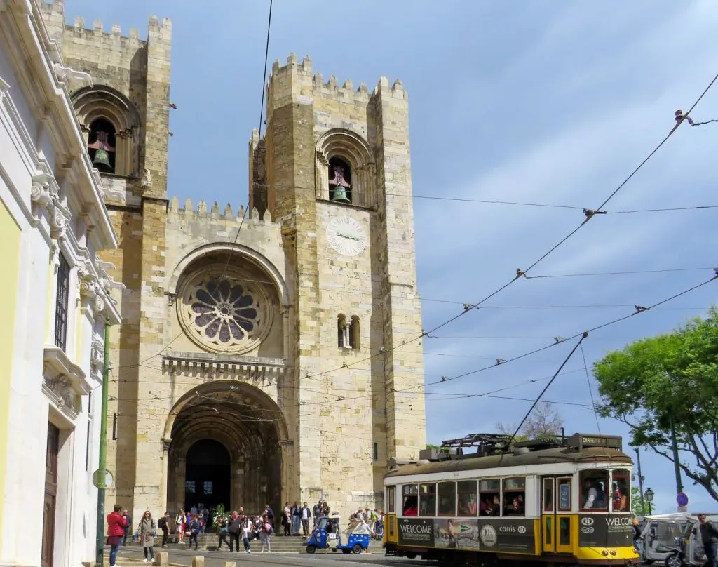 An image of Lisbon Cathedral, one of the places to visit when spending one day in Lisbon, with a yellow tram riding in front of it