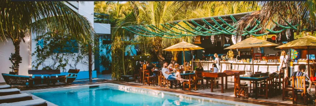 Photo of a swimming pool and people sitting in tables around it 