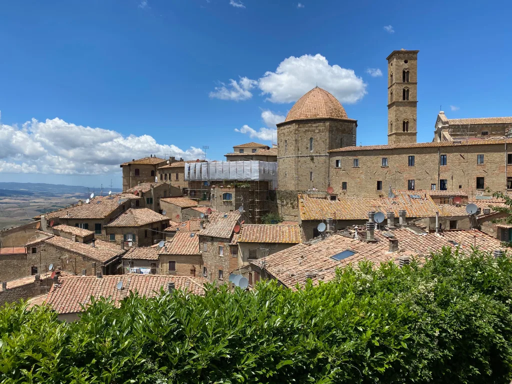 Image of buildings in Volterra, with a blue sky and a couple of clouds in the background